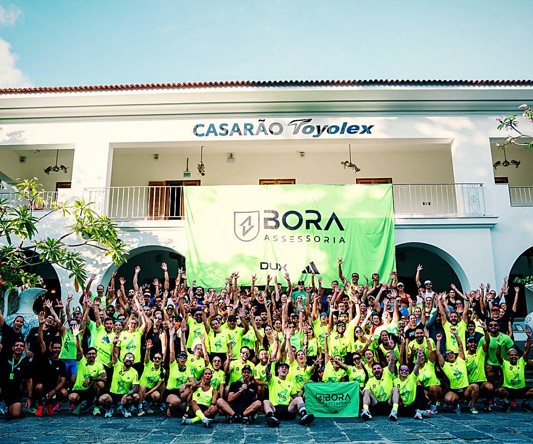 Turma da BORA reunida depois do treino, com a bandeira da assessoria ao fundo